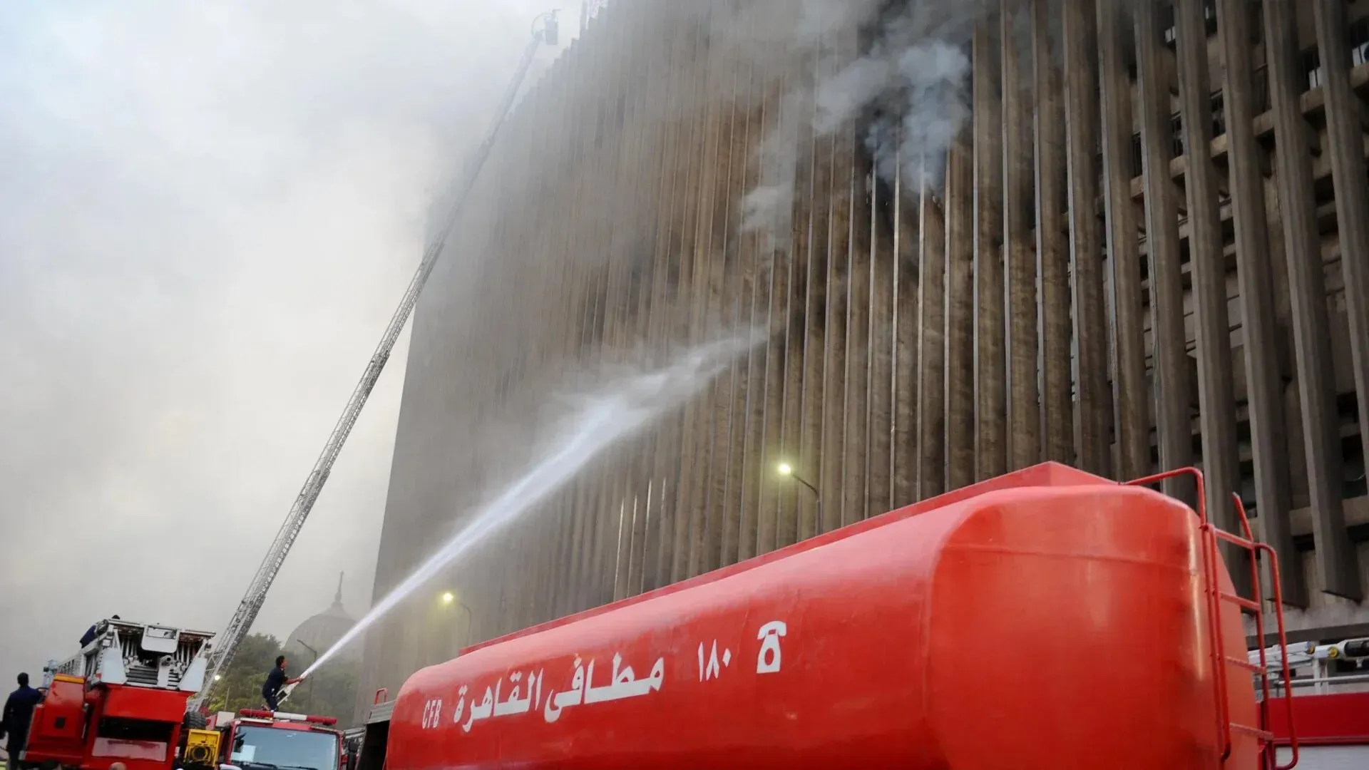حريق كبير في مركز بيانات رمسيس بالقاهرة، مع رجال الإطفاء يواجهون اللهب والدخان، مما أدى إلى شلل في أنظمة الاتصالات والمصارف.