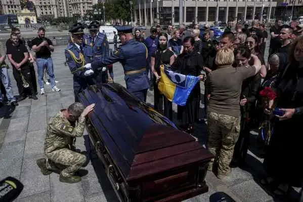 تجمع حشد من الناس في كييف لتأبين جندي أوكراني، حيث يقف ضباط في الزي العسكري بجانب تابوت خشبي ويقدمون التحية.