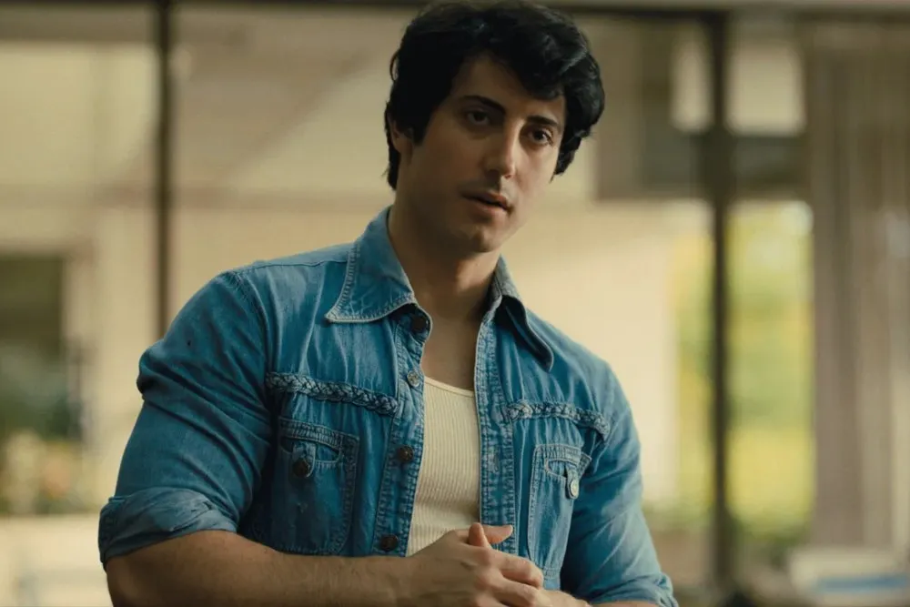 ممثل شاب يرتدي قميص جينز مفتوح وقميص داخلي أبيض، يستعد لدوره في فيلم "I Play Rocky" الذي يعيد سرد قصة كتابة وتمثيل فيلم "روكي".