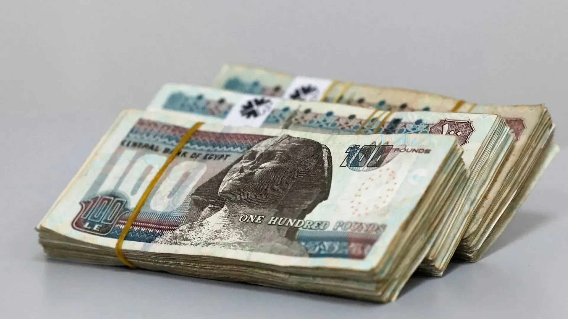 مجموعات من فئات المئة جنيه مصري، تعكس الوضع الاقتصادي الحالي في مصر وتأثير النموذج الاقتصادي الذي يسيطر عليه الجيش.