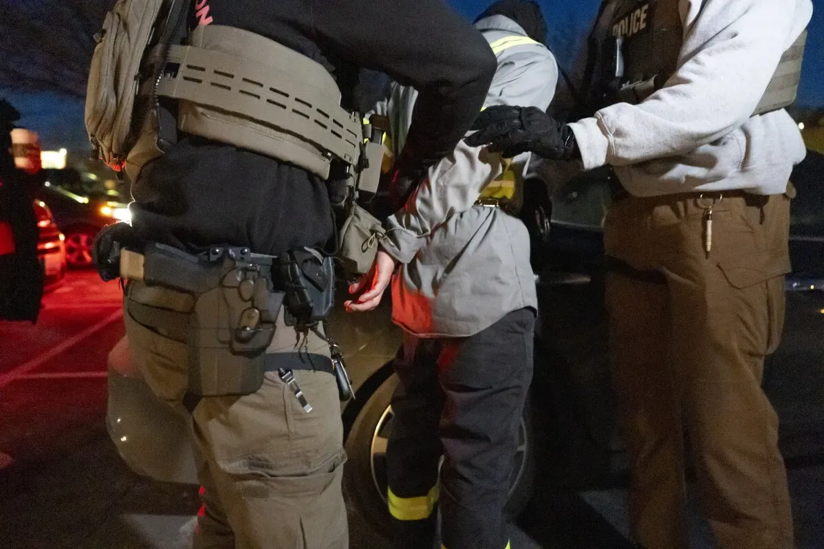 ضباط من وكالة إنفاذ قوانين الهجرة والجمارك يعتقلون شخصًا في موقف للسيارات بماريلاند، في إطار حملة لإنفاذ قوانين الهجرة.