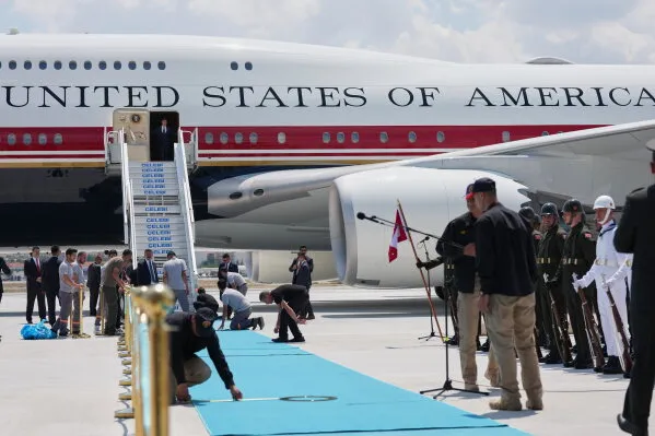 طائرة Air Force One القديمة باللون الأبيض والأزرق الفاتح في مطار مع أفراد أمن واستعدادات رسمية، تعكس قرار ترامب بالعودة بها بدلاً من الطائرة الجديدة.