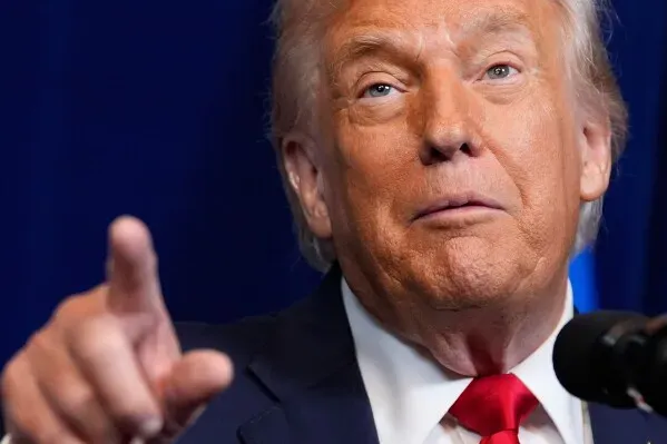 ترامب يتحدث في مؤتمر صحفي، مشيرًا بإصبعه، مع خلفية زرقاء، حيث يناقش قضايا صحته وفحوصاته الطبية الأخيرة.