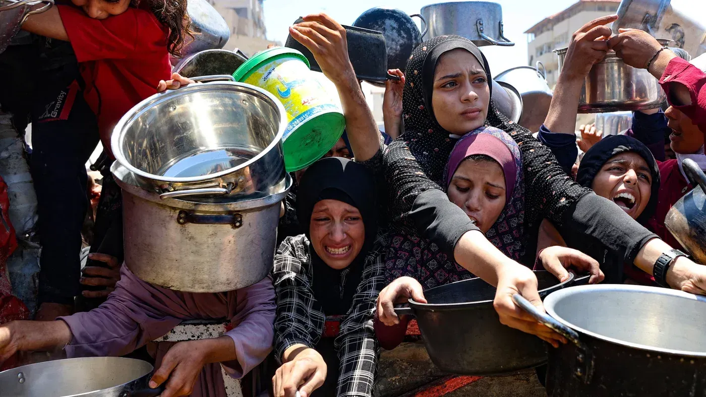 نساء وأطفال في غزة يتجمعون حول نقطة توزيع الطعام، يعبرون عن اليأس والجوع الشديد في ظل الأوضاع الإنسانية الصعبة.