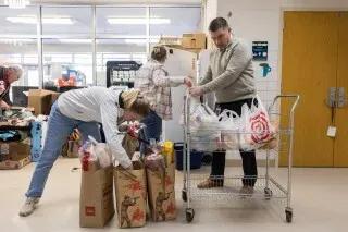 متطوعون يقومون بفرز وتوزيع المواد الغذائية في مركز مجتمعي بمينيابوليس لدعم العائلات المهاجرة في ظل الظروف الصعبة.