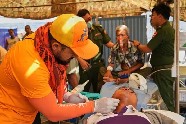 فريق طبي يعالج مصابًا في مستشفى ميداني بميانمار بعد الزلزال، مع وجود مرضى آخرين في الخلفية، مما يعكس جهود الإغاثة الدولية.