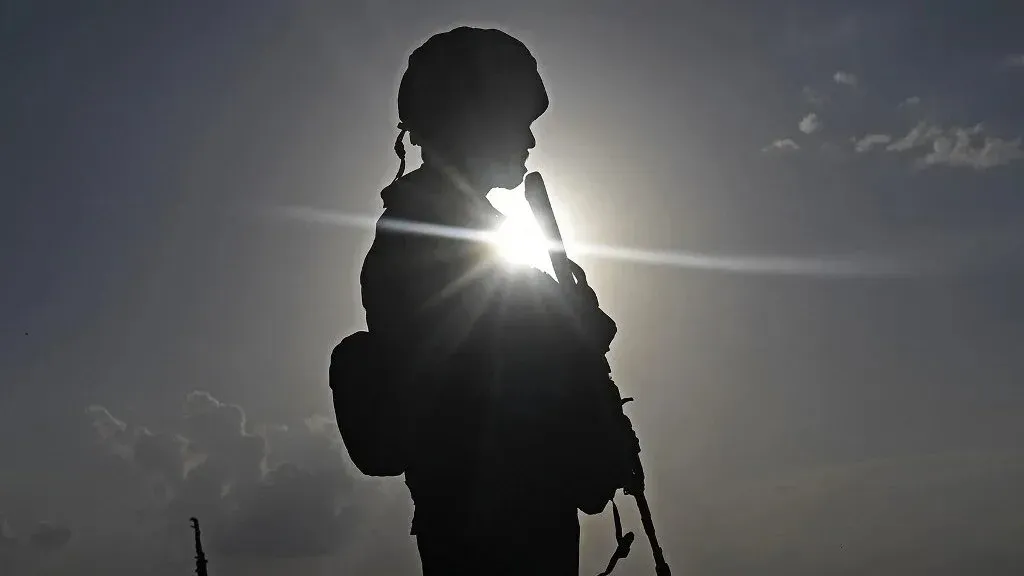 جندي يقف silhouetted أمام الشمس، مما يرمز إلى التوترات العسكرية بين الهند وباكستان في كشمير، وسط تصاعد النزاع.