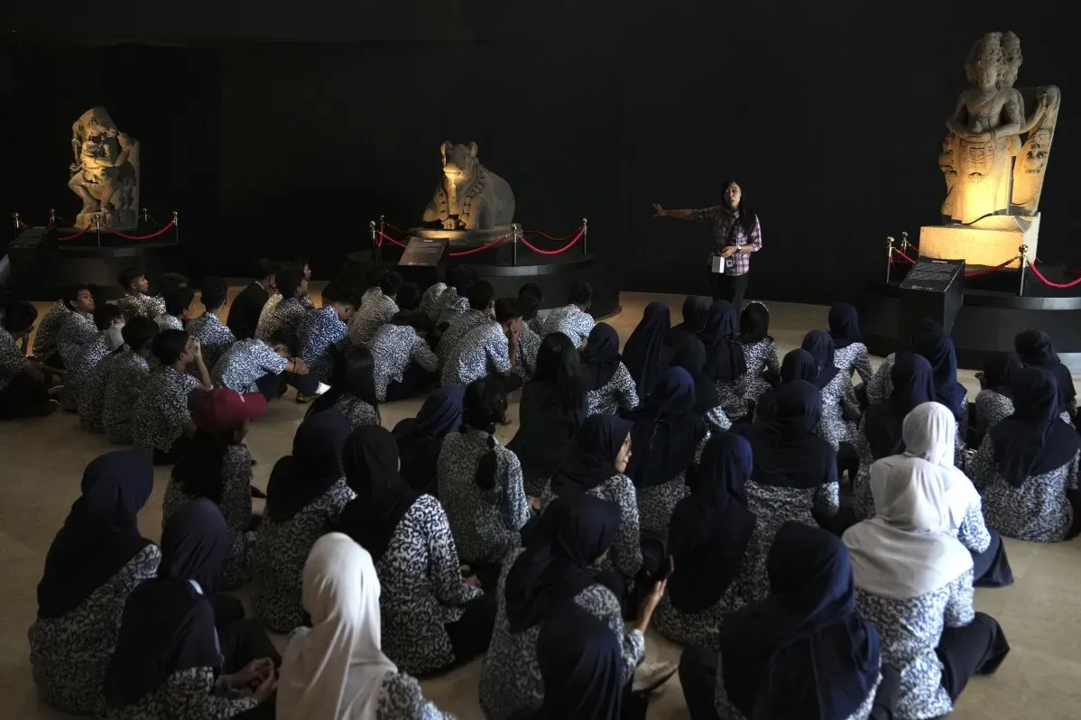 جمهور كبير يستمع إلى مرشد أثناء عرض تماثيل بوذا الحجرية في المتحف الوطني الإندونيسي، مشيراً إلى أهمية التراث الثقافي المستعاد.