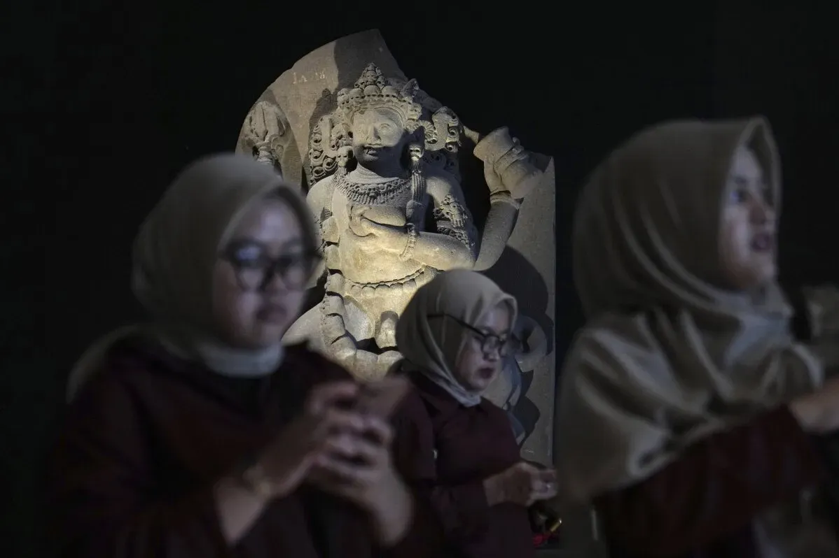 تمثال بوذا الحجري يظهر في المتحف الوطني الإندونيسي، مع زوار يتفاعلون مع القطع الأثرية الثقافية المستعادة، مما يجسد جهود إندونيسيا لاستعادة تراثها.