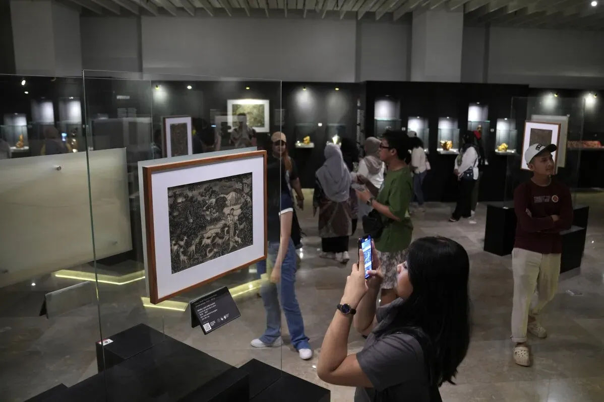 زوار يتأملون القطع الأثرية في المتحف الوطني الإندونيسي، حيث تُعرض تماثيل بوذا ومجوهرات تعود لعصور قديمة.