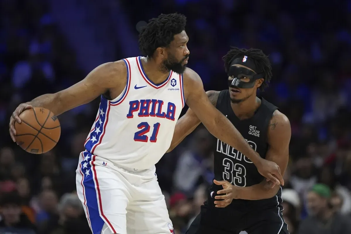 جويل إمبيد، لاعب فريق 76ers، يتحكم بالكرة أثناء مواجهة مع لاعب من فريق الخصم، وسط أجواء حماسية في مباراة كرة سلة.