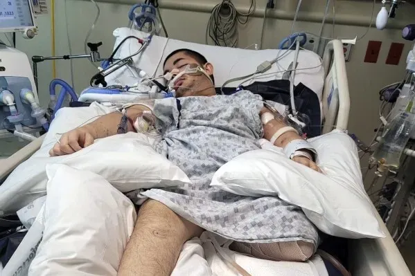 شاب مصاب بالتوحد والشلل الدماغي في المستشفى بعد تعرضه لإطلاق نار من الشرطة، مع أجهزة طبية حوله.