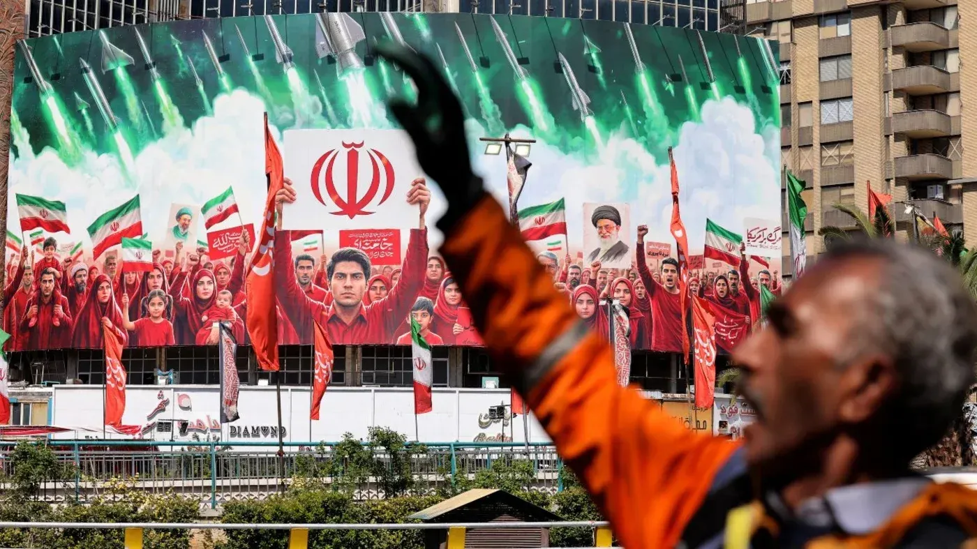 صورة تظهر حشودًا تحتفل في شوارع إيران، مع لافتات تحمل رموزًا وطنية وصورًا للقيادة، تعبيرًا عن الدعم الوطني وسط الأجواء السياسية المتوترة.