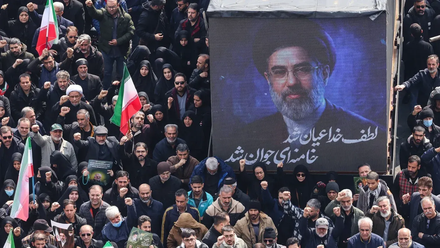 تجمع حشود من الناس في مظاهرة تأييد للقيادة الإيرانية، مع صورة للمرشد الأعلى الجديد مجتبى خامنئي في الخلفية.