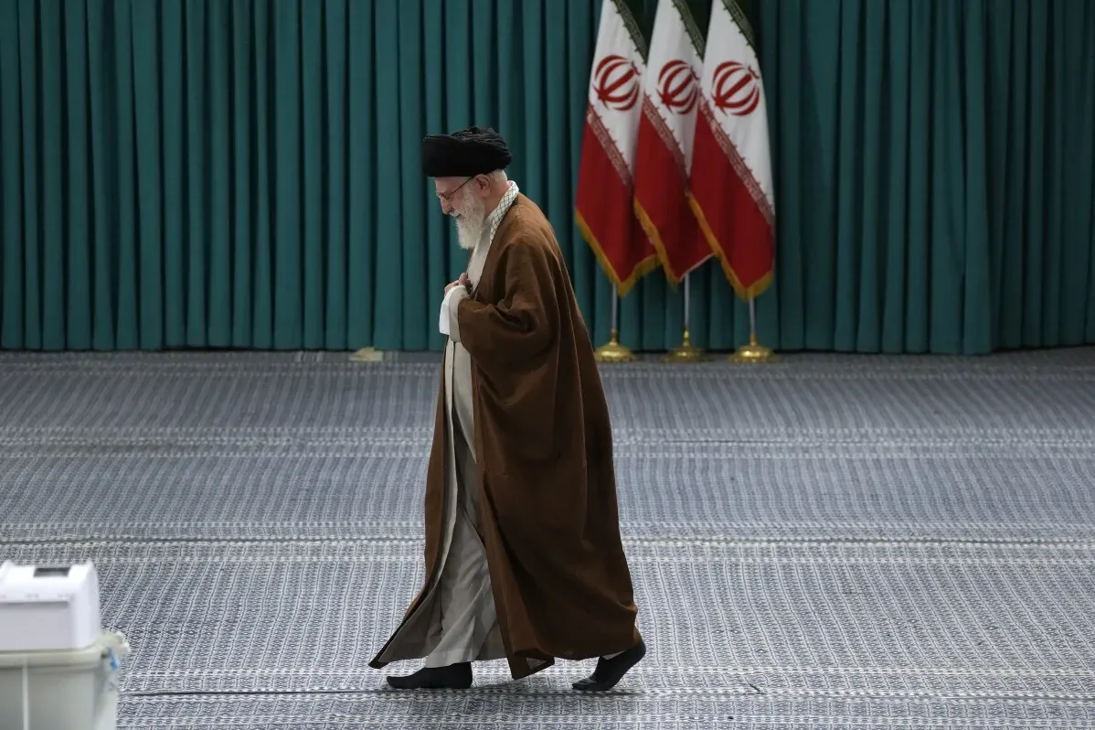 المرشد الأعلى الإيراني آية الله علي خامنئي يسير في قاعة مؤتمرات، مع ظهور العلم الإيراني خلفه، وسط أجواء سياسية متوترة.
