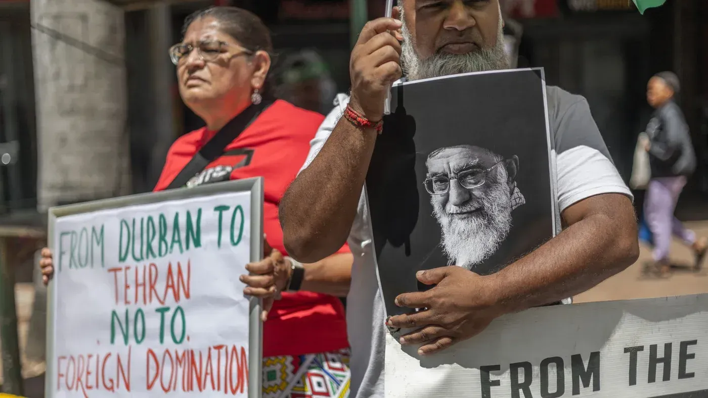 محتجون يحملون لافتات تعبر عن رفضهم للهيمنة الأجنبية، مع صورة لرجل مسن، في سياق التوترات بين إيران والولايات المتحدة.