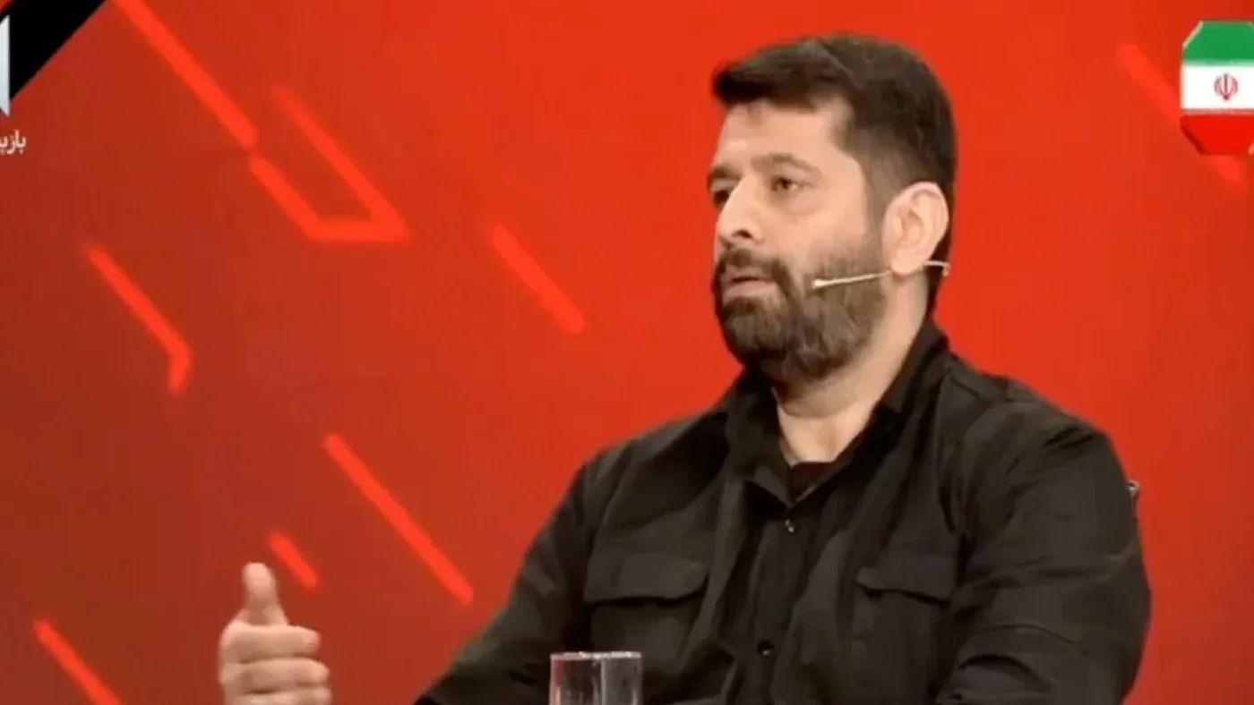 محلل أمني إيراني يتحدث في برنامج تلفزيوني عن استعداد الجيش الإيراني للتحرك ضد الإمارات والبحرين، مع خلفية حمراء.