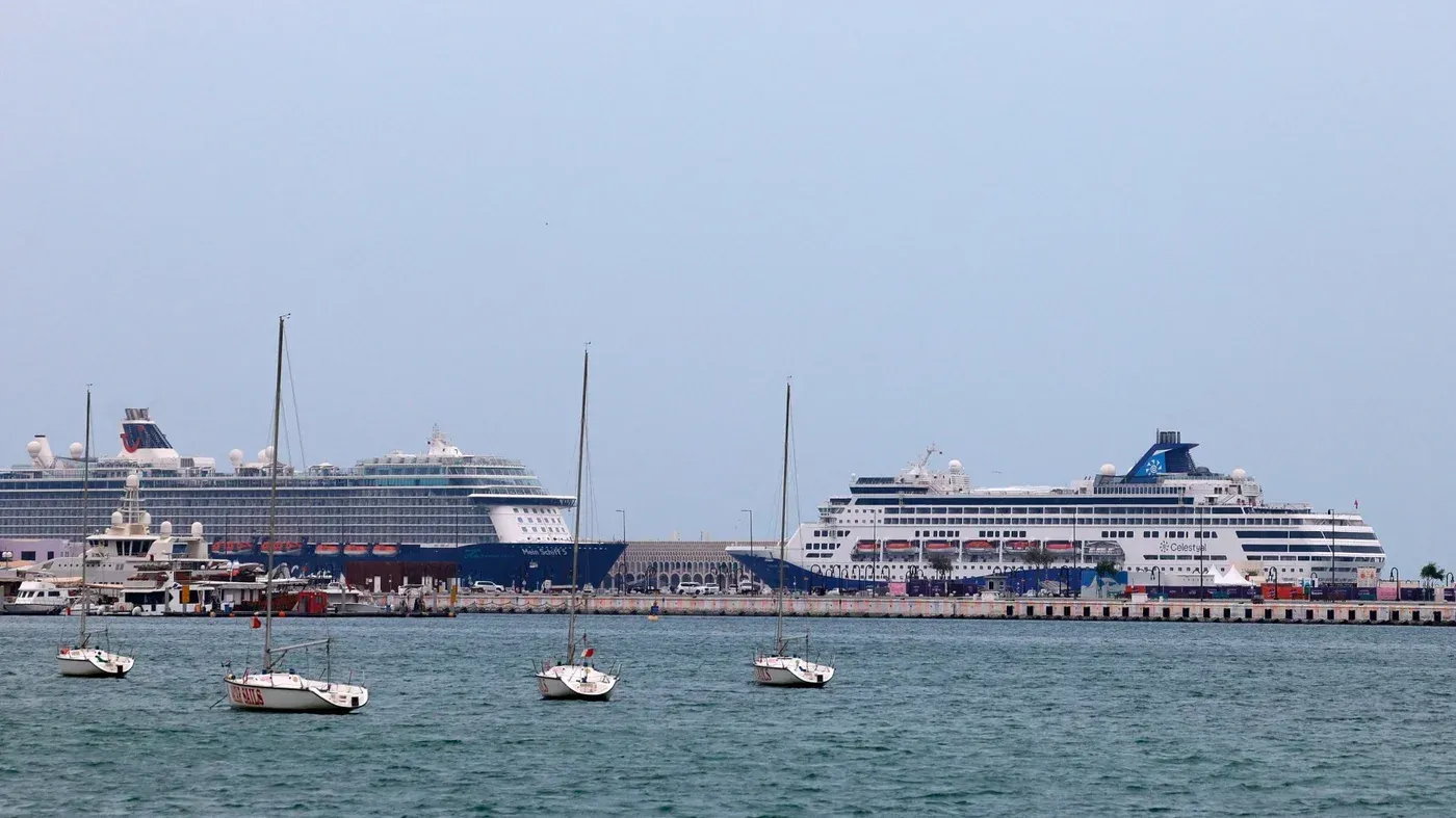 السفن السياحية عالقة في الخليج، مع وجود العديد من القوارب الصغيرة في المقدمة، مما يعكس تأثير النزاع على حركة الملاحة البحرية.