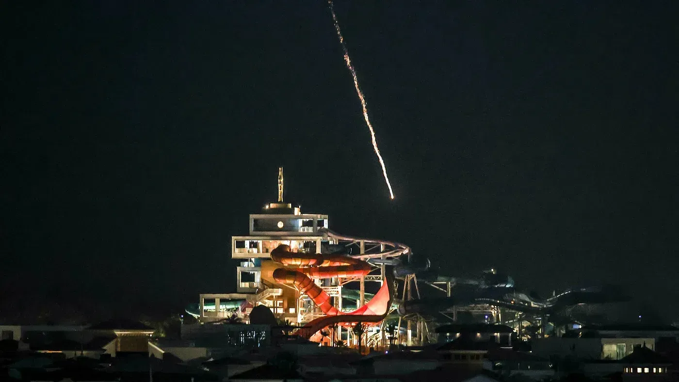 صاروخ يضيء سماء الليل أثناء إطلاقه من موقع في منطقة حضرية، مما يعكس تصاعد التوترات العسكرية في الشرق الأوسط.