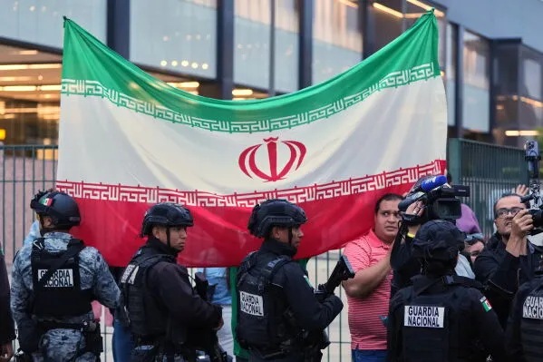 مؤيدون إيرانيون يحملون علم إيران في تيخوانا، بينما يتواجد عناصر من الحرس الوطني المكسيكي، استعداداً لمشاركة المنتخب الإيراني في كأس العالم.