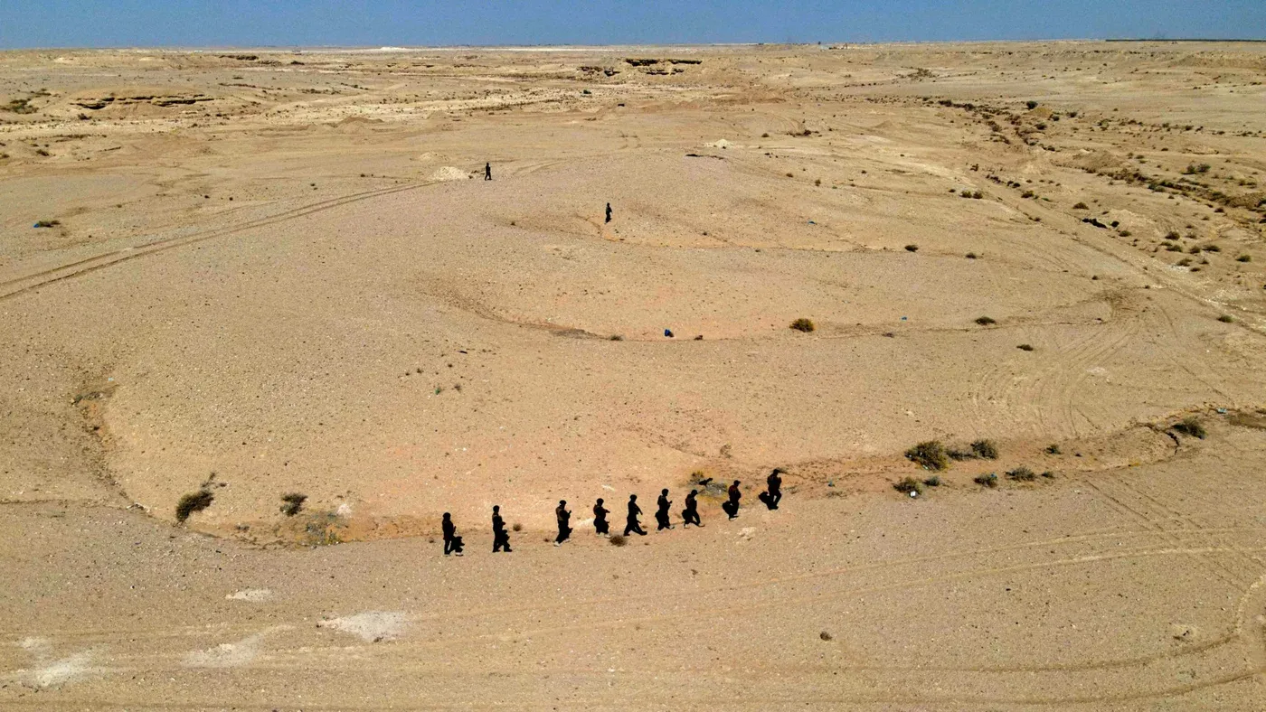 مجموعة من الأشخاص يسيرون في الصحراء الغربية العراقية، حيث تشير التقارير إلى وجود قاعدة إسرائيلية سرية خلال الحرب على إيران.