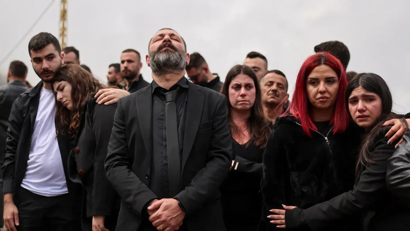 مجموعة من الأشخاص يرتدون ملابس سوداء، يعبرون عن حزنهم خلال مراسم تأبين، في ظل أجواء من التوتر بعد تصاعد النزاع في لبنان.