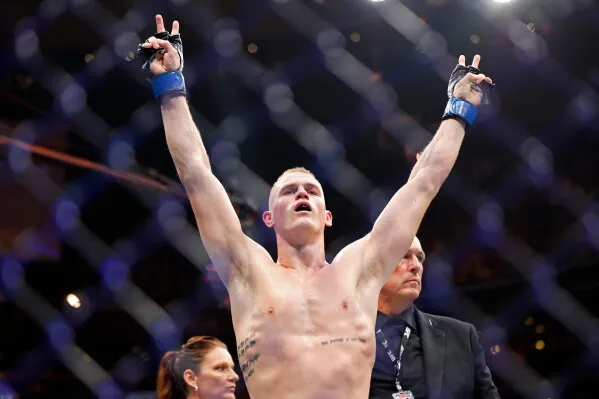 مقاتل UFC يرفع يديه انتصاراً داخل القفص في نزال بطولة فيلادلفيا، مع تركيز على سلسلة انتصارات Islam Makhachev التاريخية.