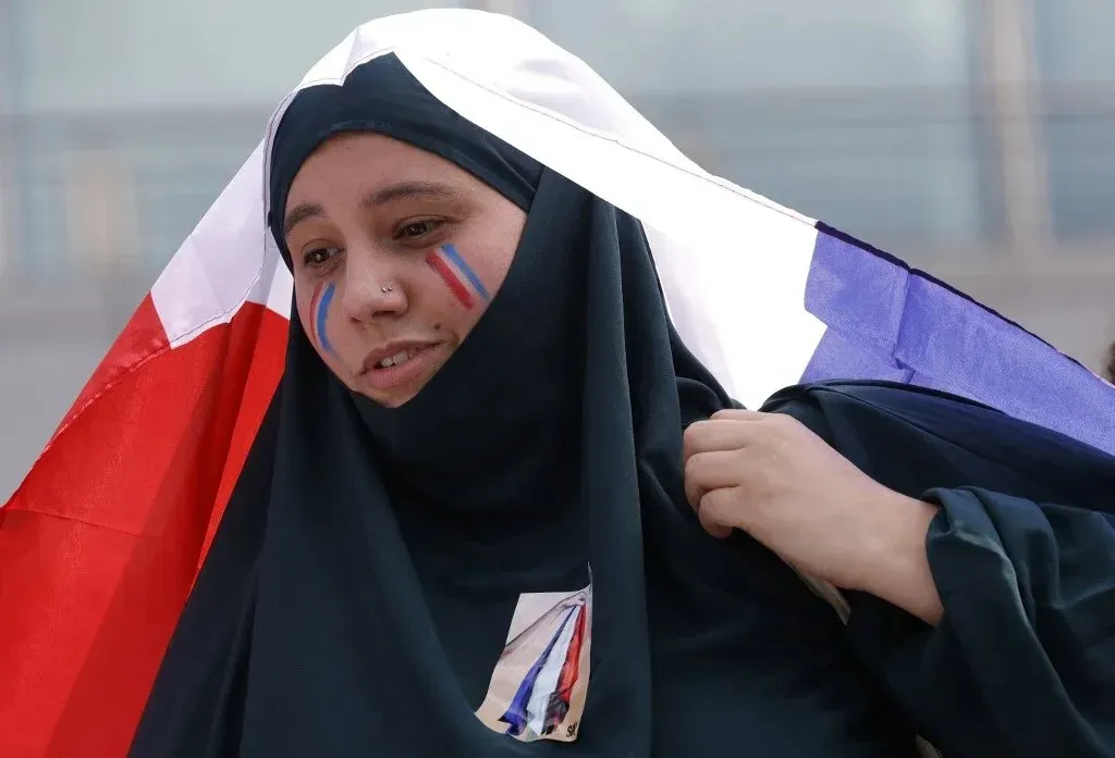 امرأة ترتدي الحجاب وتحمل علم فرنسا، تعبر عن هويتها الثقافية في سياق النقاش حول الإسلام السياسي في البلاد.