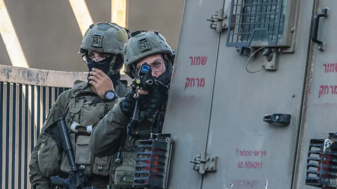 جنود إسرائيليون يرتدون زيًا عسكريًا كاملًا، أحدهم يحمل سلاحًا، أثناء تأمين منطقة في القدس.