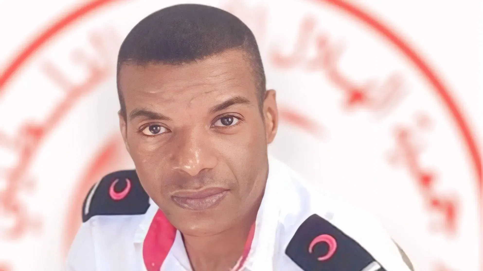 مسعف فلسطيني يرتدي زي الهلال الأحمر، يظهر في صورة خلفية بيضاء، يمثل قضية حقوق المعتقلين في ظل الأوضاع الصعبة في غزة.