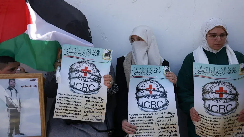 نساء فلسطينيات يحملن لافتات احتجاجية ضد منع اللجنة الدولية للصليب الأحمر من زيارة المعتقلين الفلسطينيين في السجون الإسرائيلية.