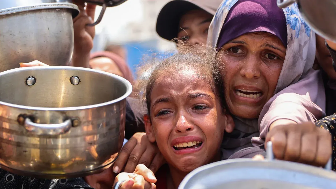 نساء وأطفال في غزة يعبرون عن معاناتهم أثناء انتظار الحصول على الطعام، وسط أزمة إنسانية متفاقمة نتيجة الحصار.