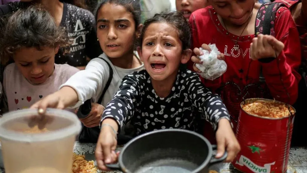 أطفال فلسطينيون في غزة يتجمعون حول الطعام، يعبرون عن القلق والجوع وسط أزمة إنسانية متزايدة نتيجة الحصار.
