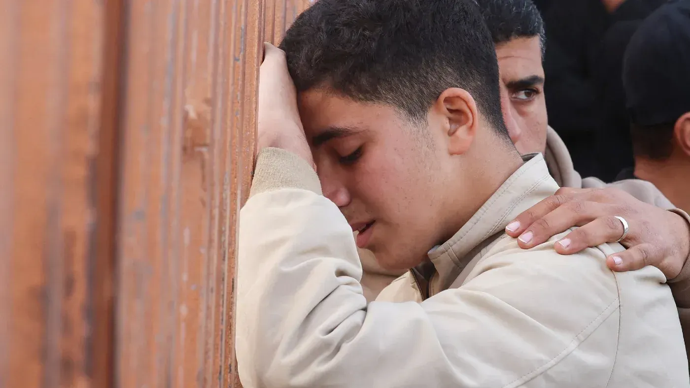 شاب فلسطيني يبكي بجوار شخص آخر، معبرًا عن الحزن بعد الغارات الإسرائيلية على غزة، التي أسفرت عن مقتل العديد من المدنيين.