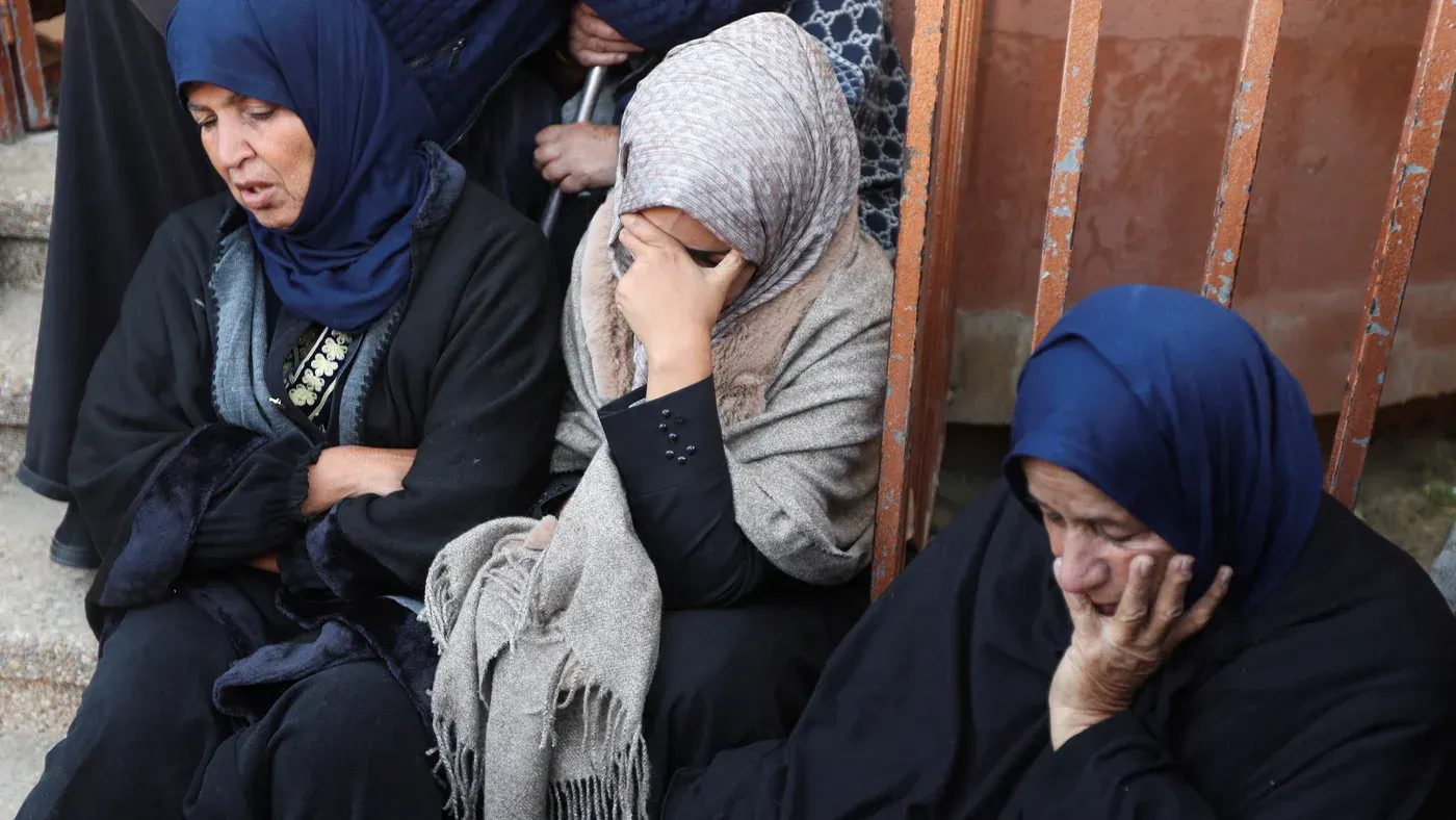 نساء فلسطينية يجلسن في حالة حزن، يعبرن عن الألم والمعاناة بعد الهجمات الإسرائيلية في غزة، وسط أجواء من التوتر والقلق.