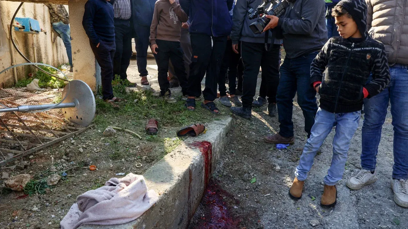 موقع الحادث في بلدة طمون، يظهر آثار الدماء والأحذية المتروكة، بينما يتجمع السكان المحليون في مكان الهجوم الإسرائيلي.