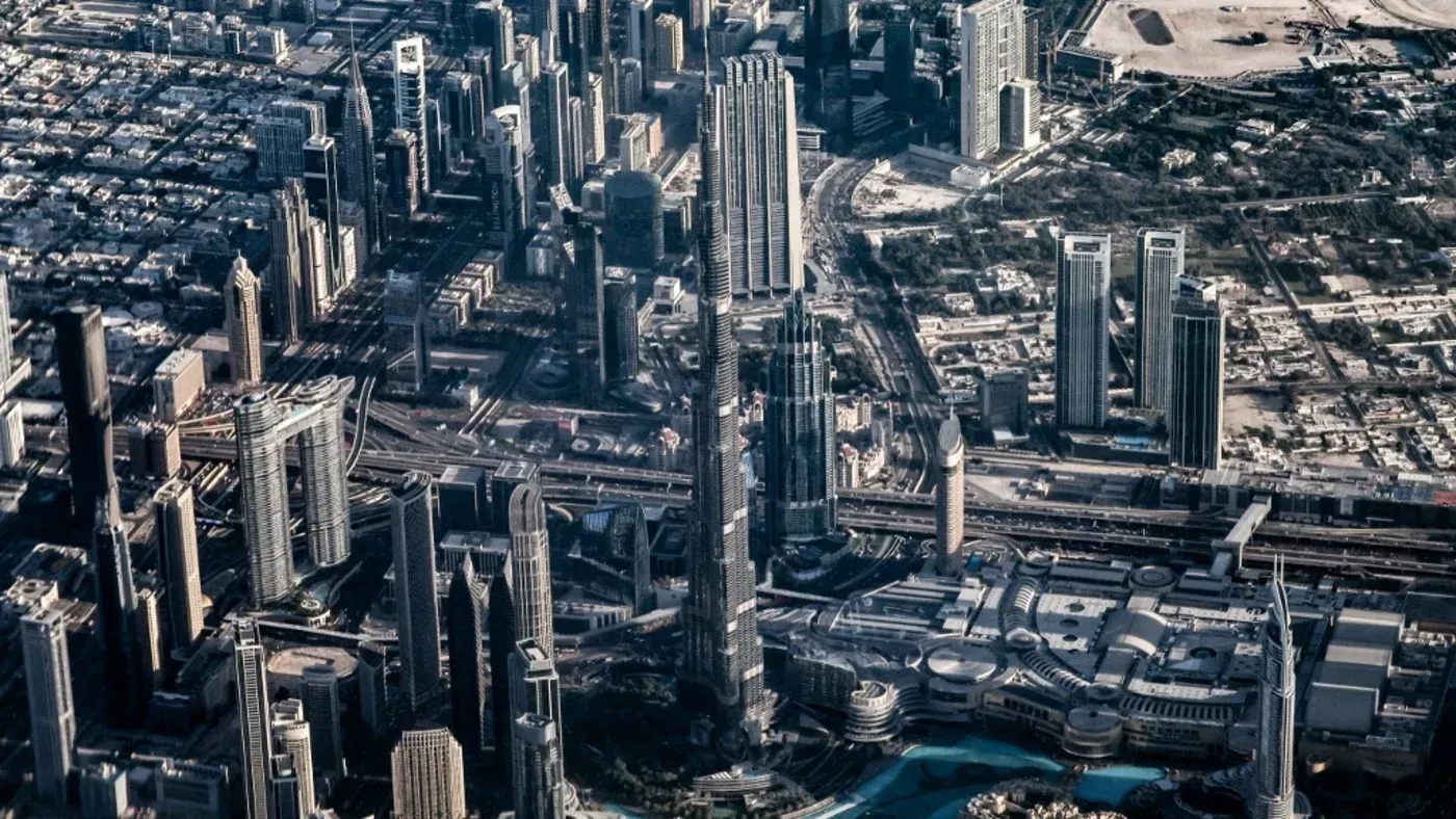 صورة جوية لمدينة دبي تظهر ناطحات السحاب الشهيرة، بما في ذلك برج خليفة، مع شبكة من الطرق والمرافق الحديثة.