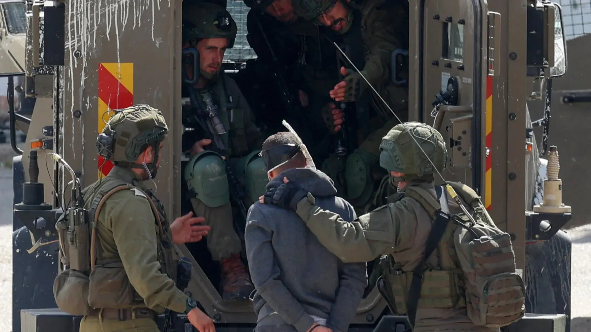 اعتقال فلسطيني من قبل جنود إسرائيليين، مع وجود مركبة عسكرية في الخلفية، في سياق تصعيد الاعتقالات بعد صفقة تبادل الأسرى.