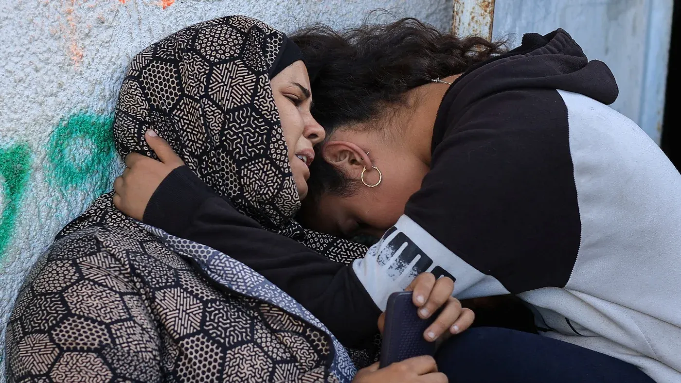امرأتان تحتضنان بعضهما في لحظة حزن، تعكسان مشاعر الألم والمعاناة في غزة وسط الأوضاع المتوترة.