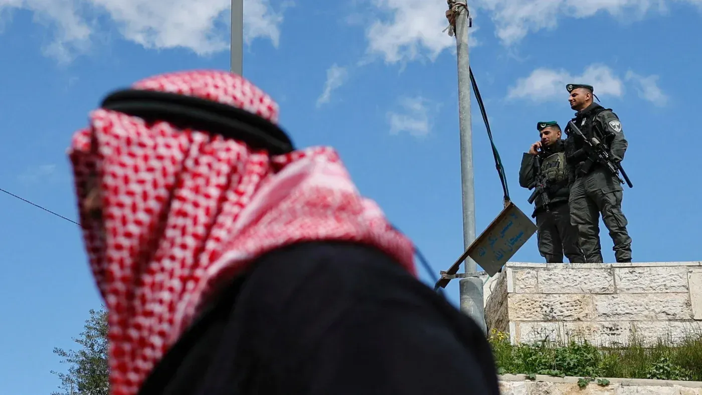 وجود شرطيين مسلحين على حافة المسجد الأقصى، مع شخص يرتدي الكوفية في المقدمة، يعكس التوترات الأمنية الحالية في القدس.