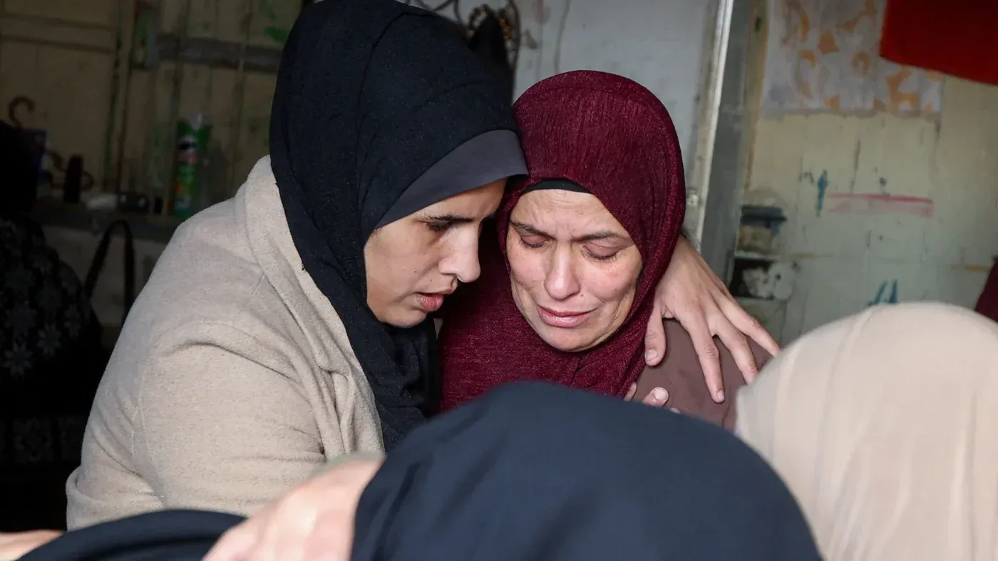 نساء فلسطينيات يتعانقن بحزن، معبرين عن مشاعر الفقد والألم بعد الهجمات الإسرائيلية في غزة.