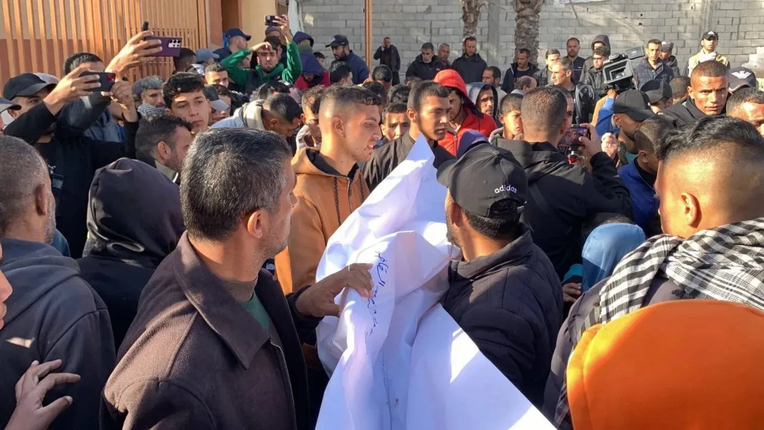 تجمع حشد من الفلسطينيين في غزة أثناء تشييع ضحايا الغارات الجوية، مع مظاهر الحزن والألم في ظل الأوضاع الصعبة التي يعيشونها.