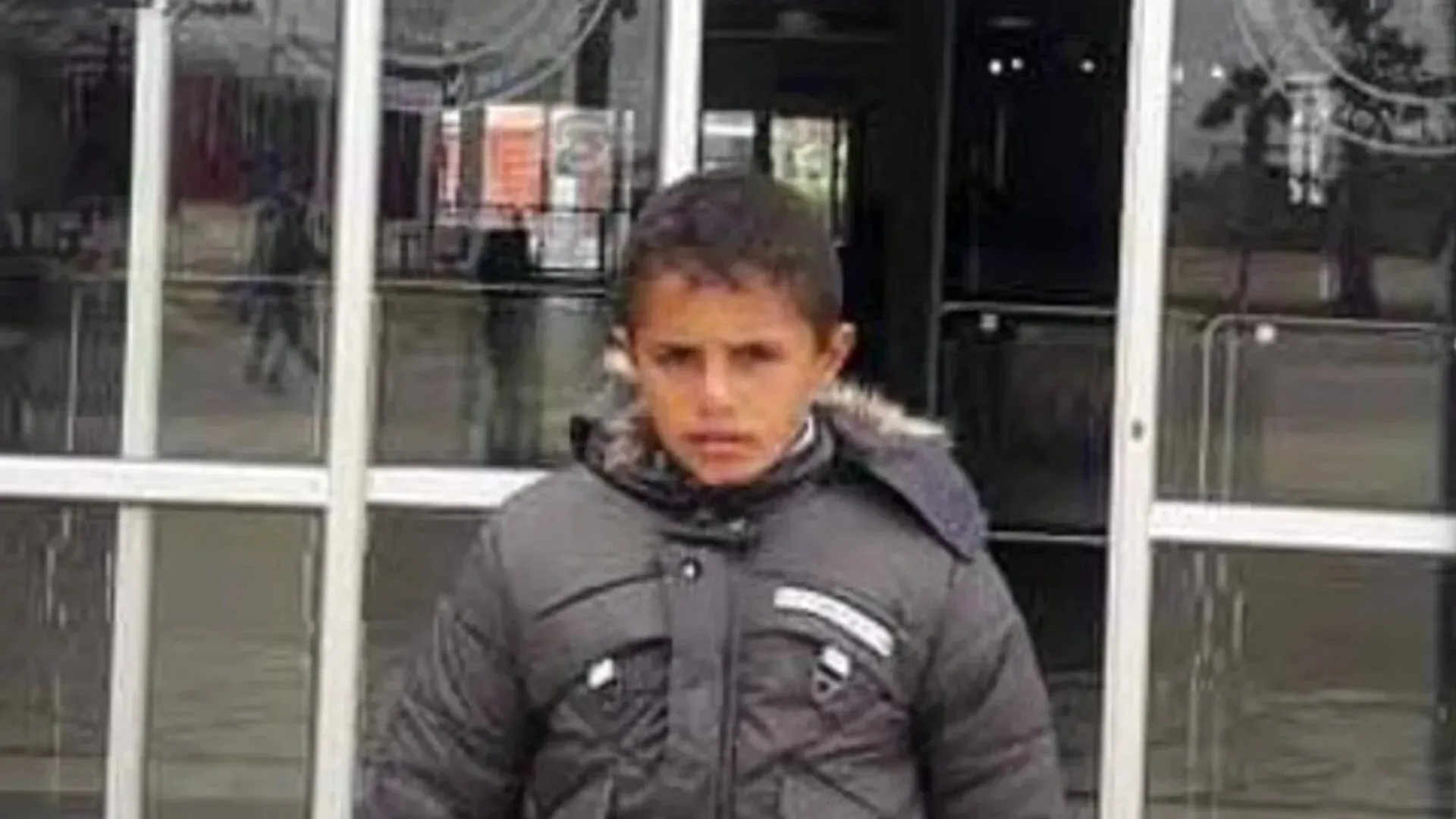 طفل فلسطيني يبلغ من العمر 12 عامًا، محمد سعيد البردويل، يقف أمام مدخل، يرتدي سترة داكنة، بعد فترة من فقدانه في حادثة مأساوية.