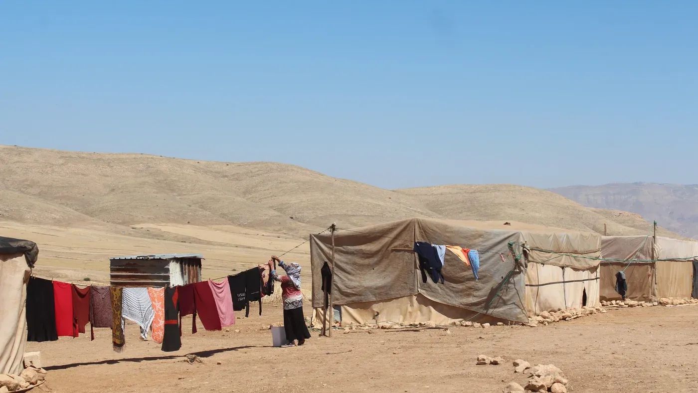 خيام فلسطينية في تجمع رعوي بالضفة الغربية مع ملابس معلقة على حبال في مشهد يعكس حياة الفلسطينيين في مناطق التهجير بسبب اعتداءات المستوطنين.