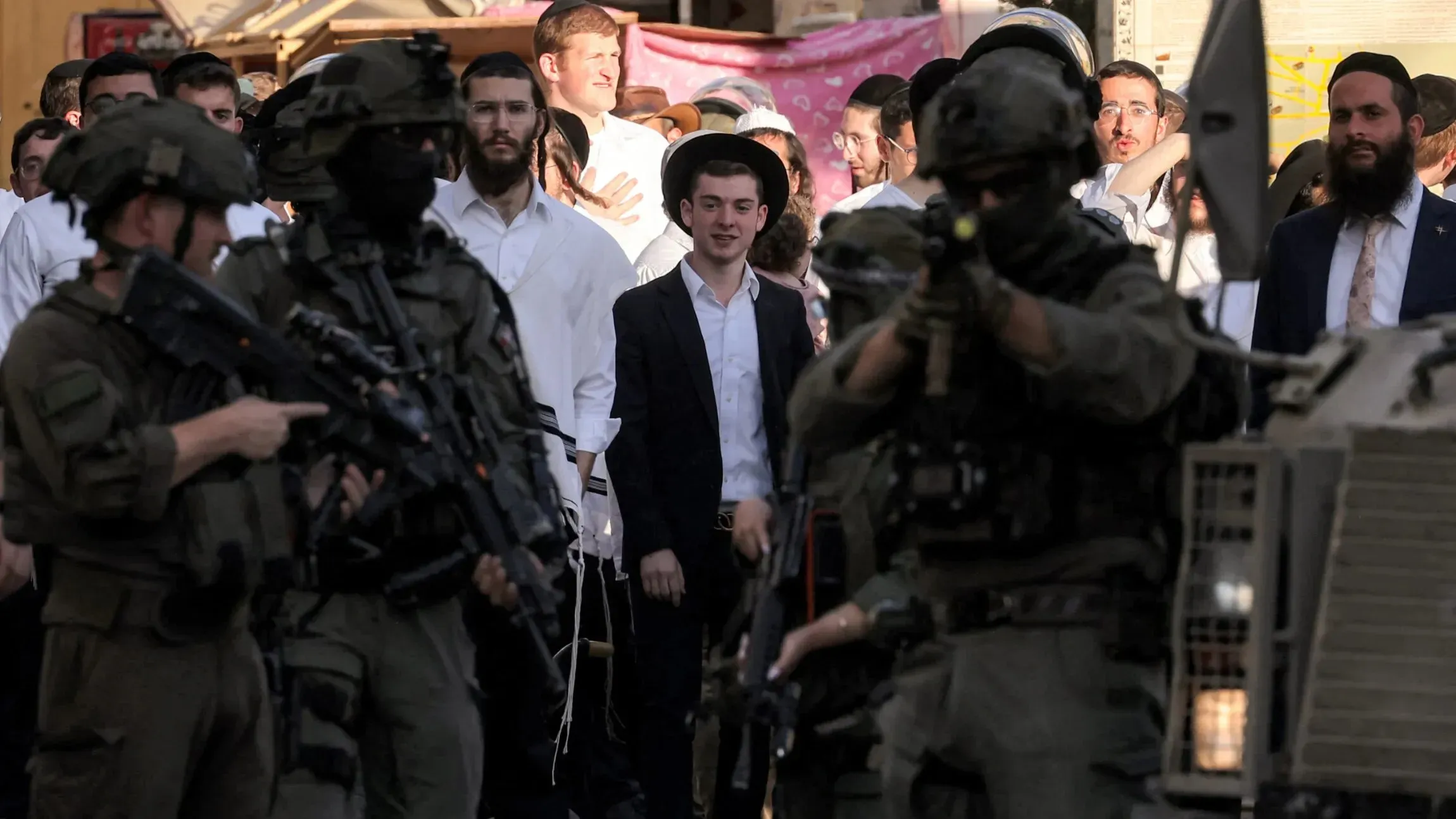 مواجهات بين جنود إسرائيليين ومستوطنين في كفر مالك، حيث يظهر الجنود مسلحين بينما يتواجد مستوطنون في الخلفية.
