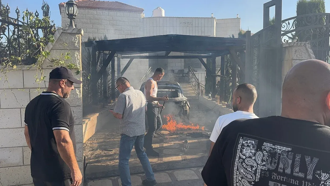 رجال فلسطينيون يحاولون إخماد حريق في سيارة أمام منزل متضرر جراء هجوم مستوطنين في قرية صرّة بنابلس بالضفة الغربية.