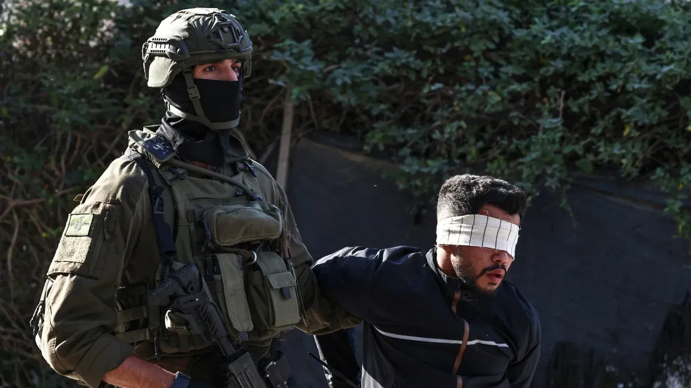 جندي إسرائيلي يرافق شاب فلسطيني معصوب العينين، في سياق مزاعم عن محاولة ابتزاز عائلة فلسطينية في الضفة الغربية.