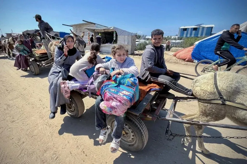 عائلة فلسطينية تستخدم عربة تجرها حيوانات لنقل الأمتعة في رفح، وسط أزمة إنسانية خانقة بسبب الحصار والقتال.