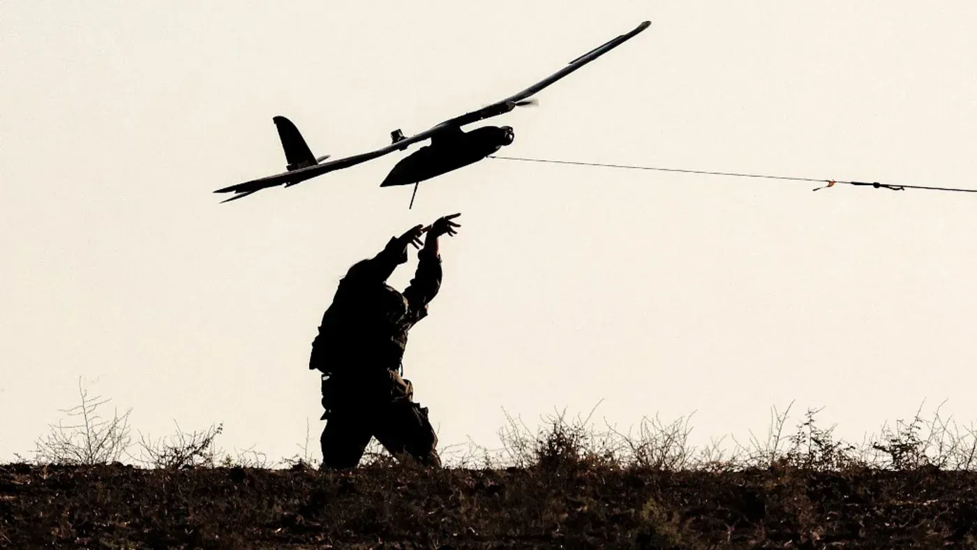 جندي إسرائيلي يطلق طائرة مسيرة في منطقة مفتوحة، مما يعكس التقدم التكنولوجي في المجال العسكري وسط التوترات المستمرة.