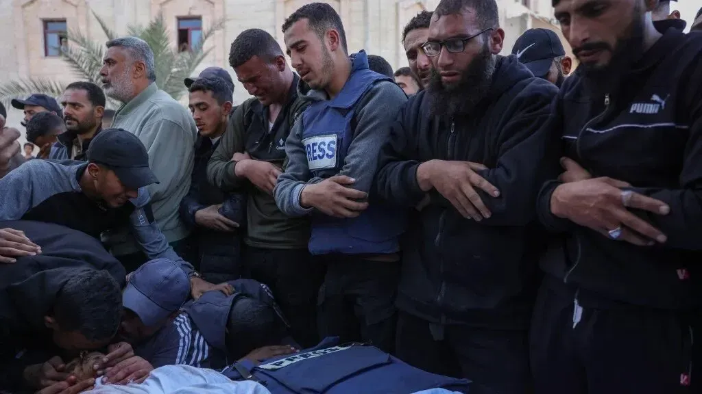 تجمع حشود من الصحفيين الفلسطينيين في جنازة، يعبرون عن الحزن لفقدان زملائهم الذين قُتلوا في الصراع الإسرائيلي على غزة.